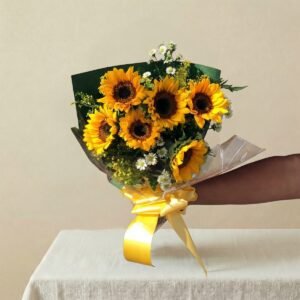 una mano sosteniendo un bouquet de seis girasoles