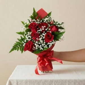Una mano sosteniendo un bouquet de seis rosas rojas